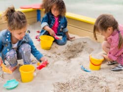 Three Young Girls playing in the sand at Juniors Day Nursery.