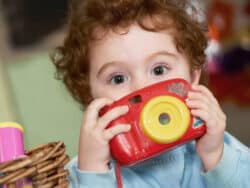 Pre-school child with camera at Juniors Day Nursery.