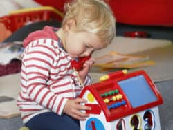 Girl playing with a phone at Juniors Day Nursery.