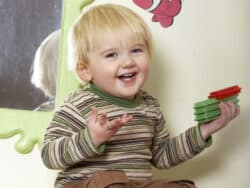 Smiley boy playing with bricks at Juniors Day Nursery.