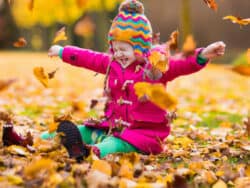 Girl playing with leaves at Juniors Day Nursery.