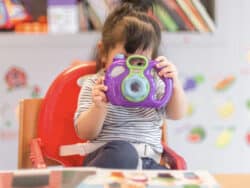 Young girl playing with a camera at Juniors Day Nursery.