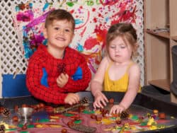 Two pre-school children playing on the sensory table at Juniors Day Nursery.