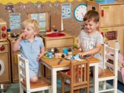 Pre-school children role playing in the toy kitchen at Juniors Day Nursery.