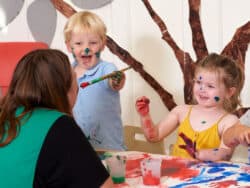 Pre-school children having fun painting at Juniors Day Nursery.