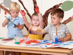 Three children painting at Juniors Day Nursery.