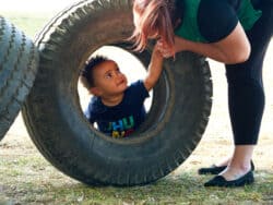 Child climbing on a car tyre in the garden of Juniors Day Nursery.