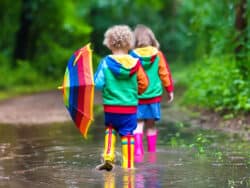 Two children playing in puddles outside Juniors Day Nursery.