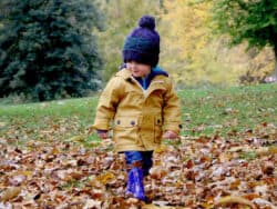 Young child playing in leaves at Juniors Day Nursery.